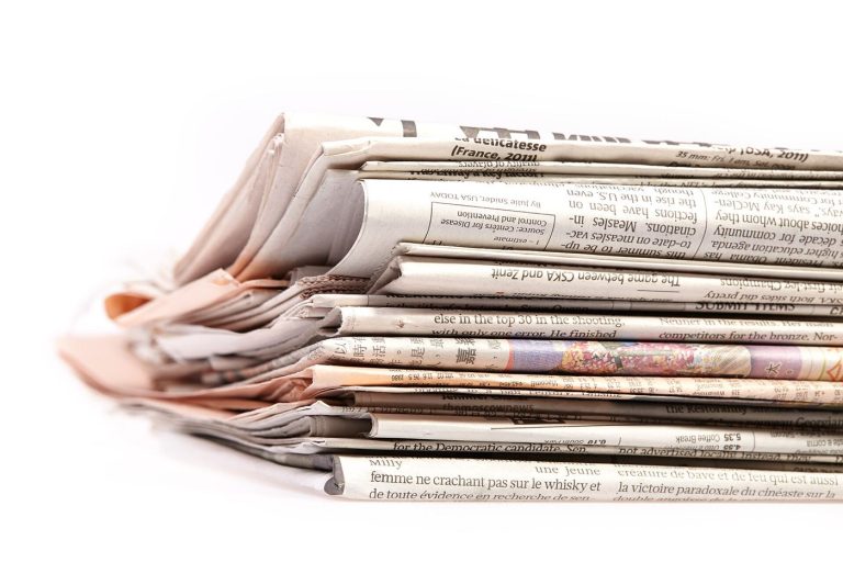 Satire Is Struggling to Keep Up With the News A stack of newspapers on a table beside a coffee cup
